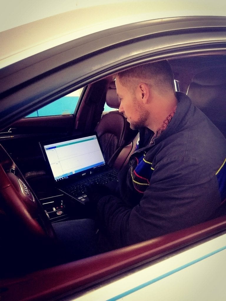 Technik ve vozidle provádí diagnostiku motoru přes notebook.